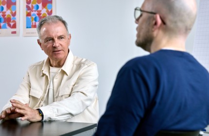 Das Bild zeigt einen freiwilligen Mentor des Projekts Tandem in einem Beratungsgespräch mit einem Stellensuchenden.